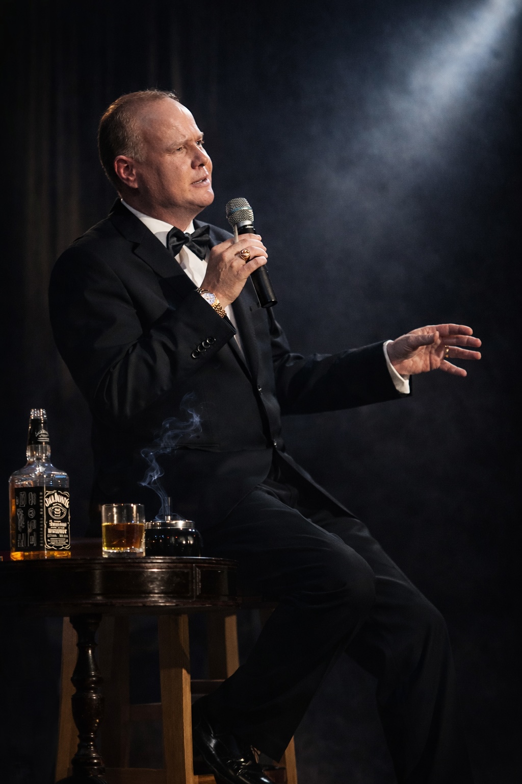 Tom O'Hara singend am Tisch mit Whiskyflasche